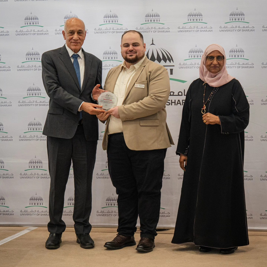 Ahmad receiving a recognition plaque at the University of Sharjah